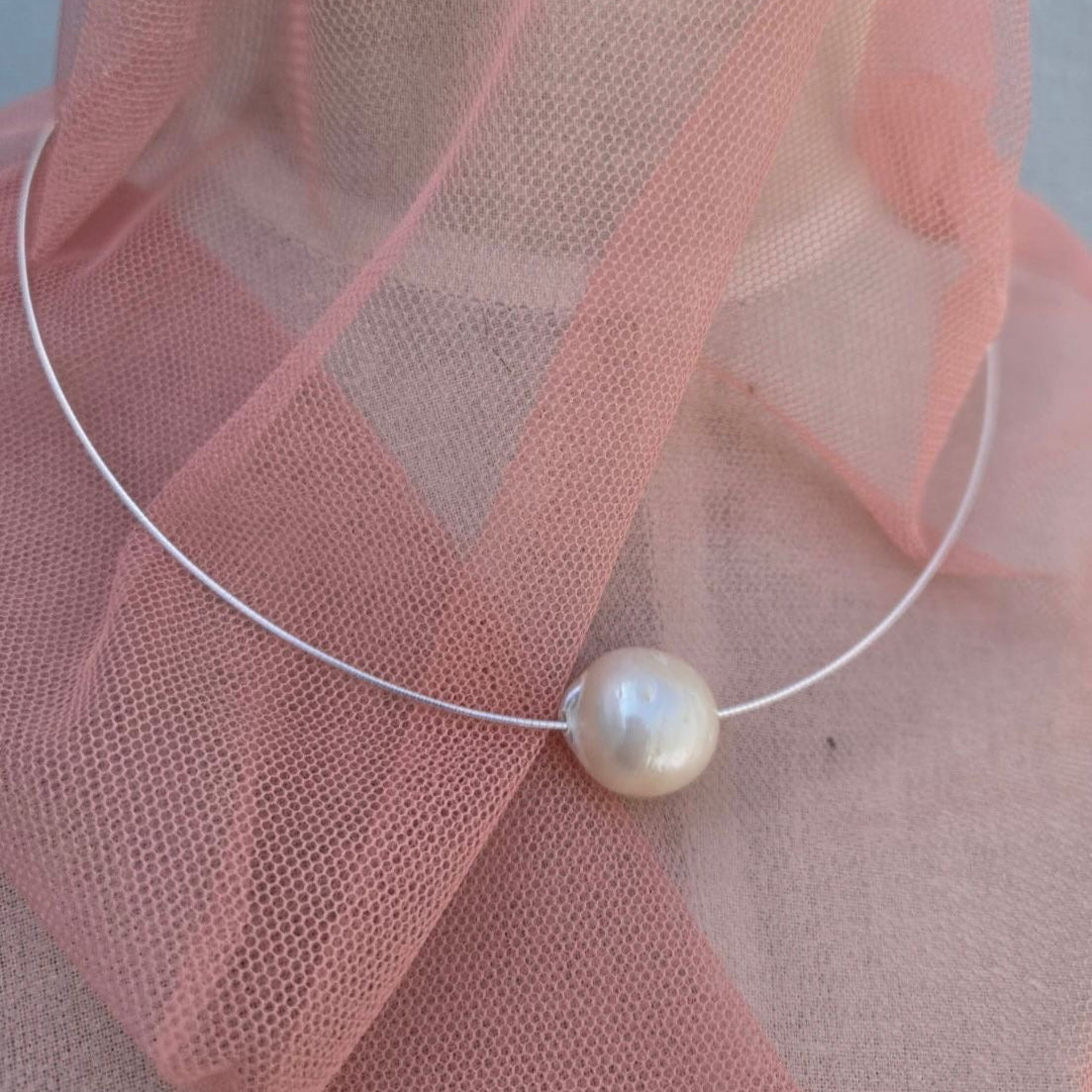 Pearl necklace on a pink fabric background
