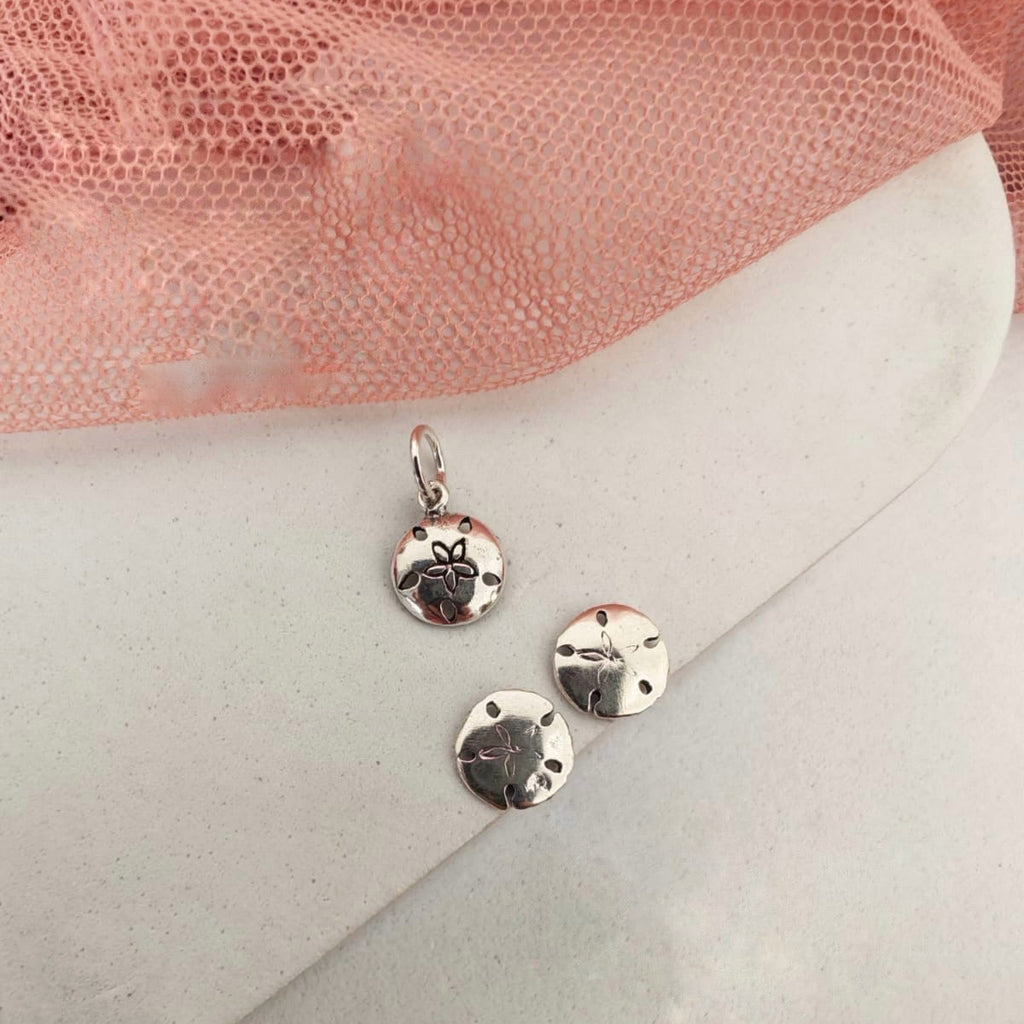 Silver earrings on a white envelope with pink fabric in the background
