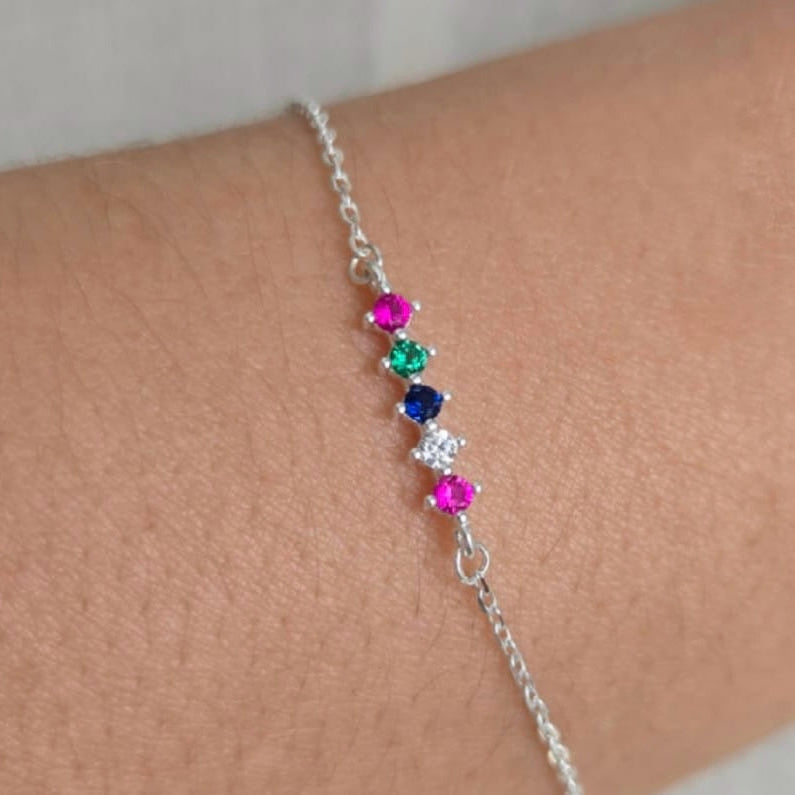 Silver bracelet with colorful gemstones on a wrist against a neutral background