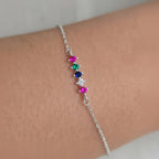 Silver bracelet with colorful gemstones on a wrist against a neutral background