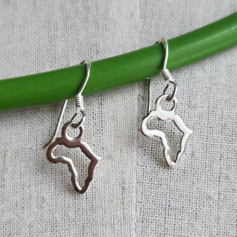 Silver horse-shaped earrings hanging on a green stick against a textured fabric background