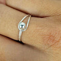 A sterling silver ball-shaped ring on a person's finger, viewed from the side.