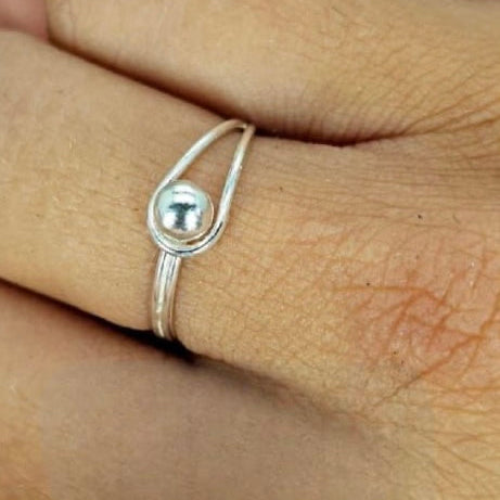 A sterling silver ball-shaped ring on a person's finger, viewed from the side.