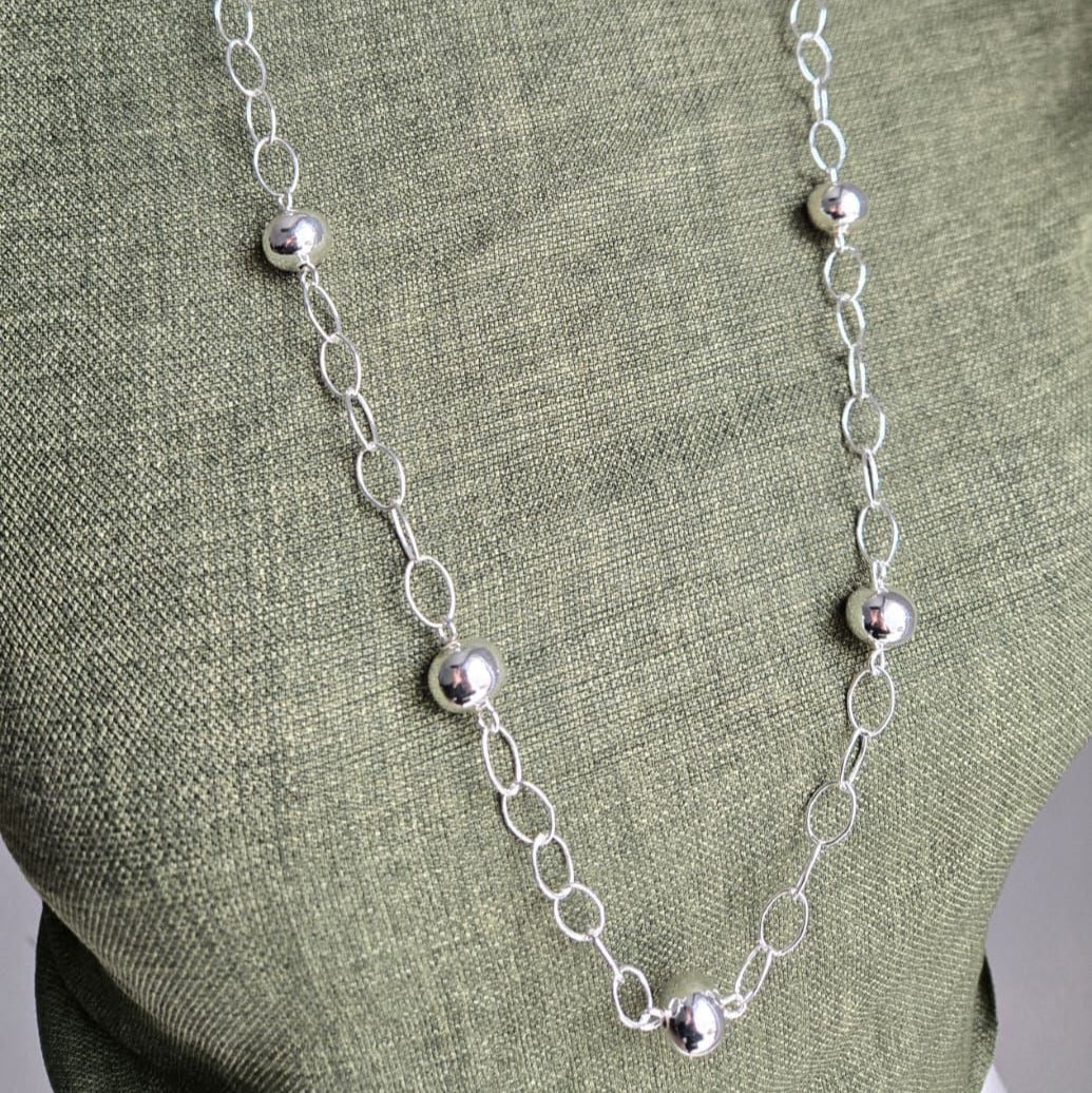 Silver necklace on a green fabric background
