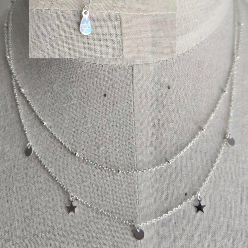 Silver necklace with star-shaped pendants on a gray background