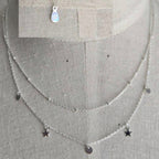 Silver necklace with star-shaped pendants on a gray background
