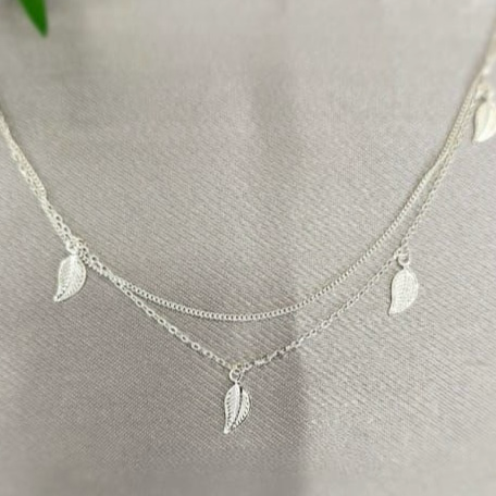 A sterling silver double necklace with detailed tiny leaves hanging from it, displayed on a white background.