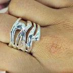 A sterling silver ring with a modern pattern detail, held on a person's finger.