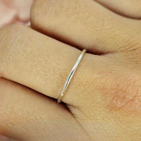 A sterling silver band ring worn on a person's finger, showing a simple and sleek design.
