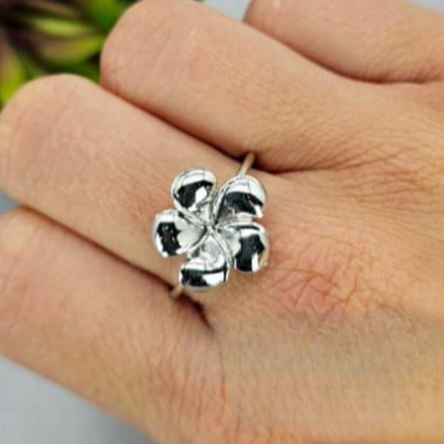 A person's hand wearing a sterling silver ring with a floral design.