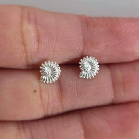 Silver stud earrings on a person's hand