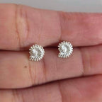 Silver stud earrings on a person's hand
