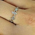 A sterling silver band ring with an integrated leaves design, displayed on a person's finger.