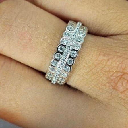 A woman's hand displaying a sterling silver three-row cubic zirconia band ring on her finger.