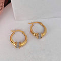 Gold hoop earrings with embedded stones on a white surface