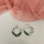 Silver earrings with abalone shell inlay on a white surface with pink fabric in the background