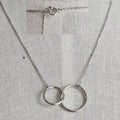 Silver necklace with interlocking rings on a gray fabric background