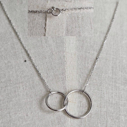 Silver necklace with interlocking rings on a gray fabric background