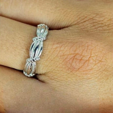A sterling silver folding band ring worn on a person's finger, displaying a intricate pattern.