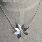 Silver necklace with a flower pendant on a mannequin.
