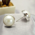 A pair of 16mm white Mabe pearl stud earrings set in sterling silver, displayed on a textured surface.