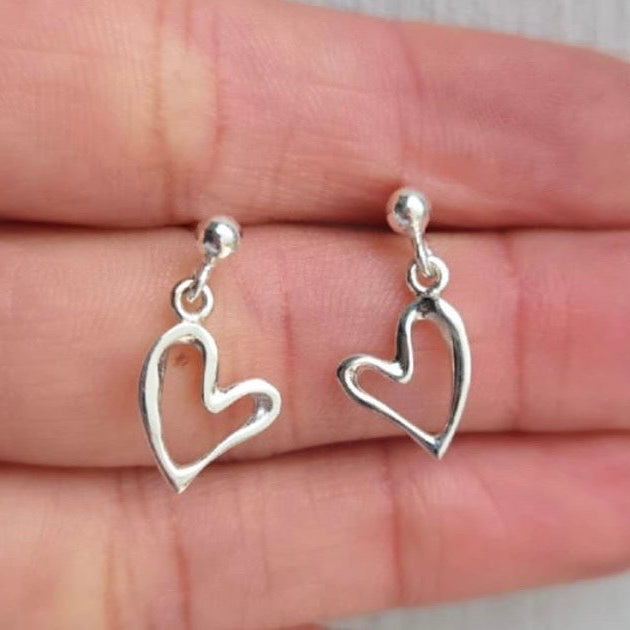 Silver heart-shaped earrings on a hand