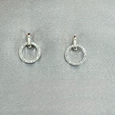 Silver hoop earrings with small round stones on a gray surface.