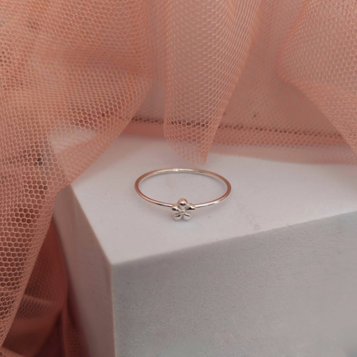 Rose gold ring on a white box with pink fabric in the background