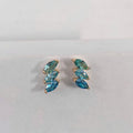 Pair of gold earrings with blue gemstones on a light gray background