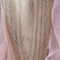 Silver chain necklace on a mannequin with a soft pink fabric background