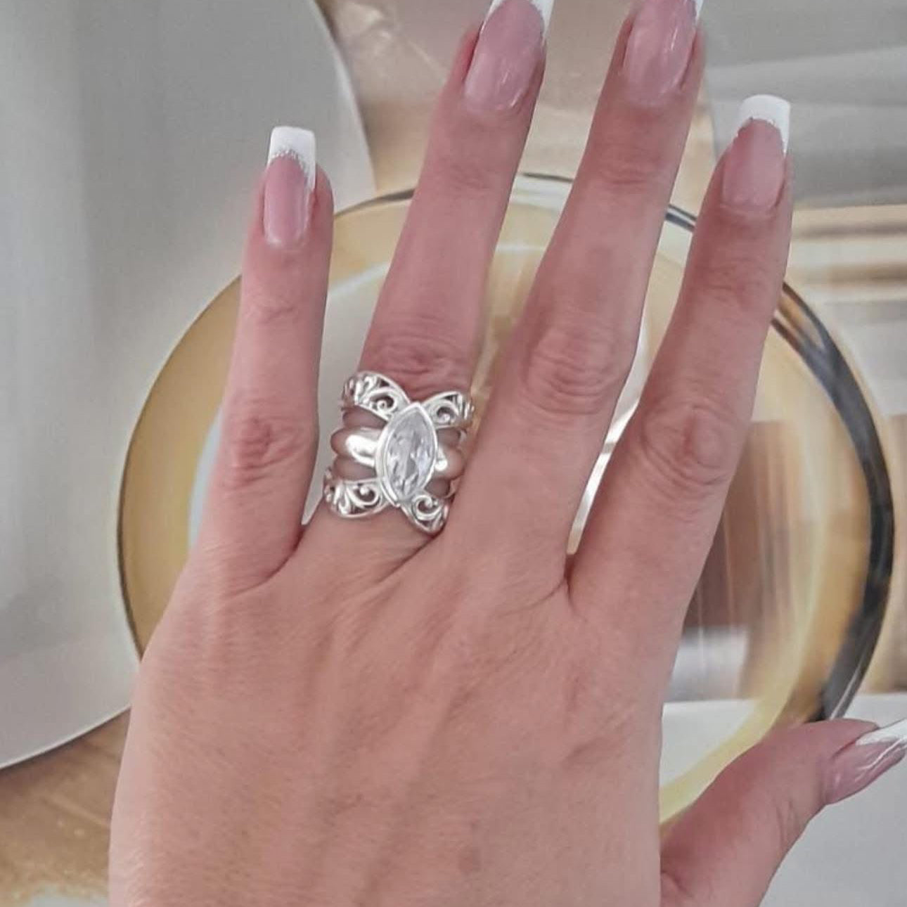 A person's hand displaying a sterling silver oval ring with a cubic zirconia center stone.
