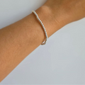 A sterling silver bracelet with 3mm balls on an elastic band, displayed on a person's wrist.