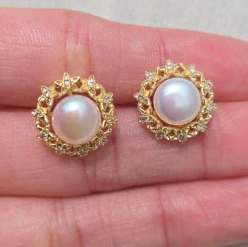 Pearl earrings with gold settings on a hand