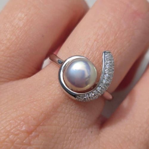 Silver ring with a pearl on a person's finger