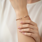 A rose gold plated sterling silver mesh bracelet lying on a surface with a floral pattern.