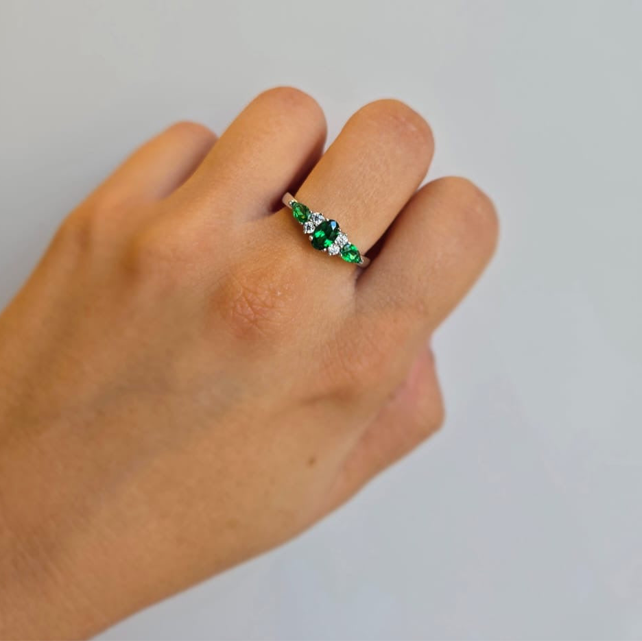 A sterling silver ring with green and clear cubic zirconia stones set in a bobble-style mounting, worn on a person's finger.