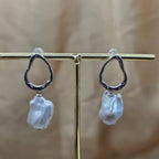 Pearl earrings on a gold stand with a blurred background