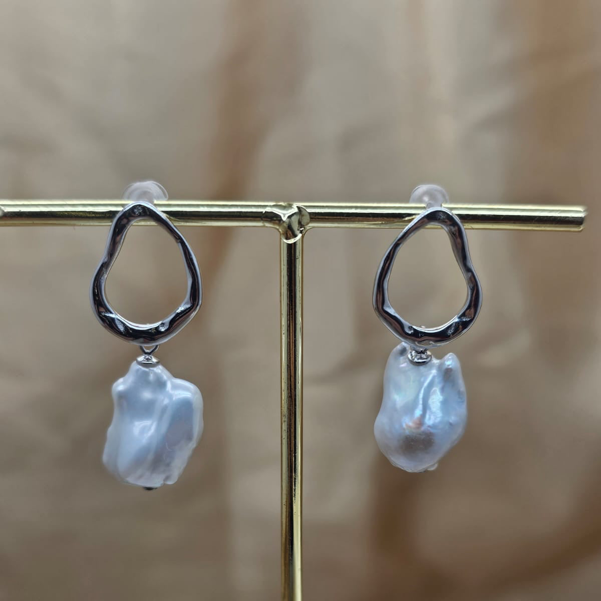 Pearl earrings on a gold stand with a blurred background