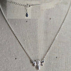 Silver bee necklace on a light gray background