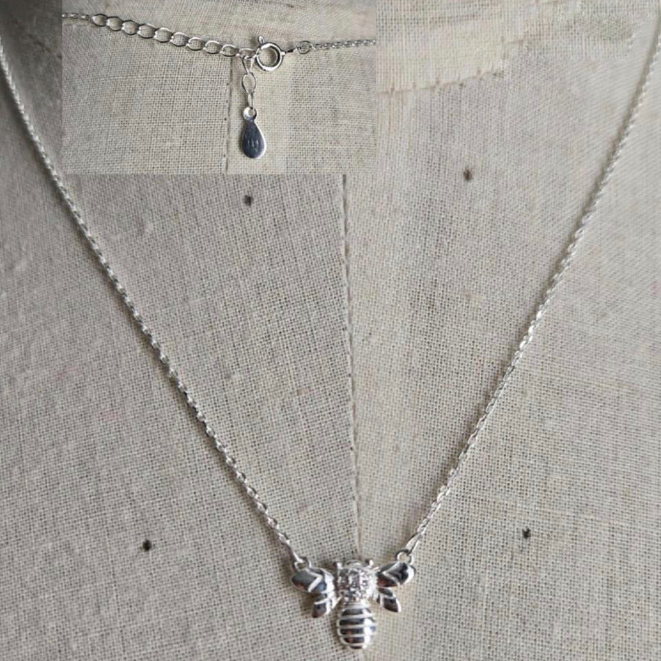 Silver bee necklace on a light gray background