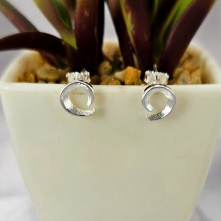A pair of sterling silver open circle stud earrings displayed in a white ceramic plant pot.