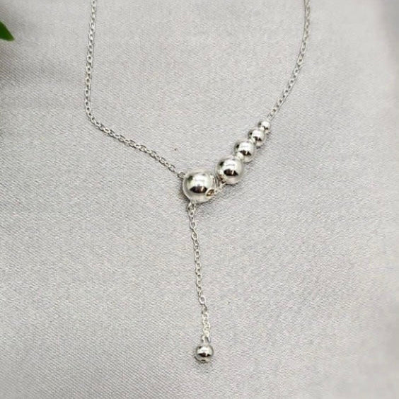 A sterling silver necklace with a series of ball details on a chain, displayed against a light background.