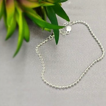 A sterling silver bracelet with tiny ball details, laid out on a flat surface.