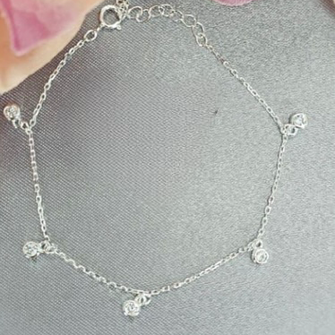 A sterling silver bracelet with cubic stones set in a tube, displayed on a surface with a blurred background.