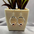 A pair of sterling silver drop earrings with rose gold plated sliding balls, displayed against a neutral background.