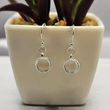 Sterling silver chain hoop earrings displayed in a white container with a green plant background.