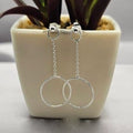 A pair of sterling silver large circle chain drop earrings displayed on a white pot with a green plant.
