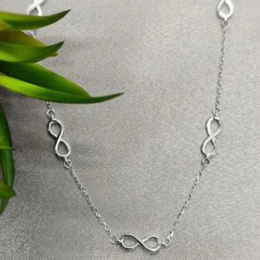 A sterling silver necklace with infinity signs integrated into the chain design, displayed against a neutral background.