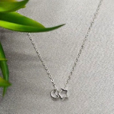 A sterling silver necklace with a sliding moon and star pendant, displayed against a neutral background.