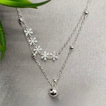A sterling silver necklace with floral details and small spherical embellishments, displayed against a neutral background.